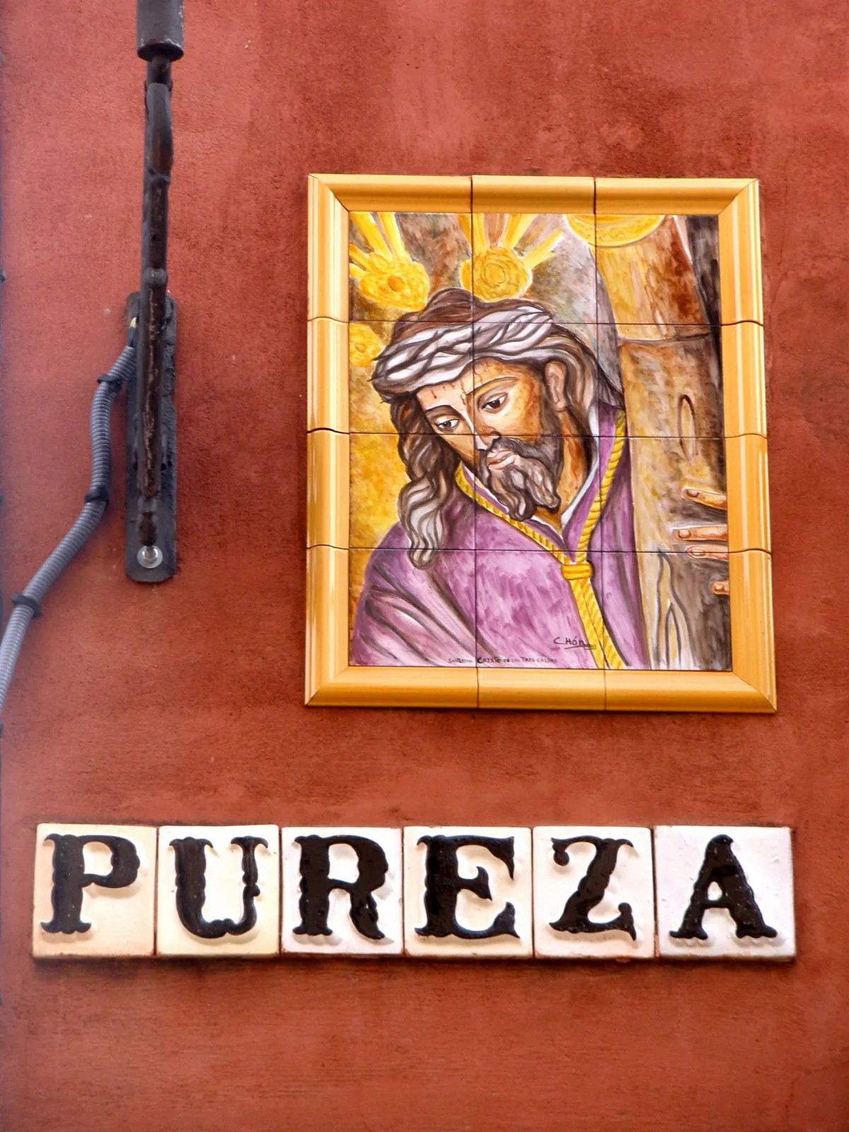 Keramický obraz Krista nad obkladačovou pouliční cedulí Pureza na Calle Pureza